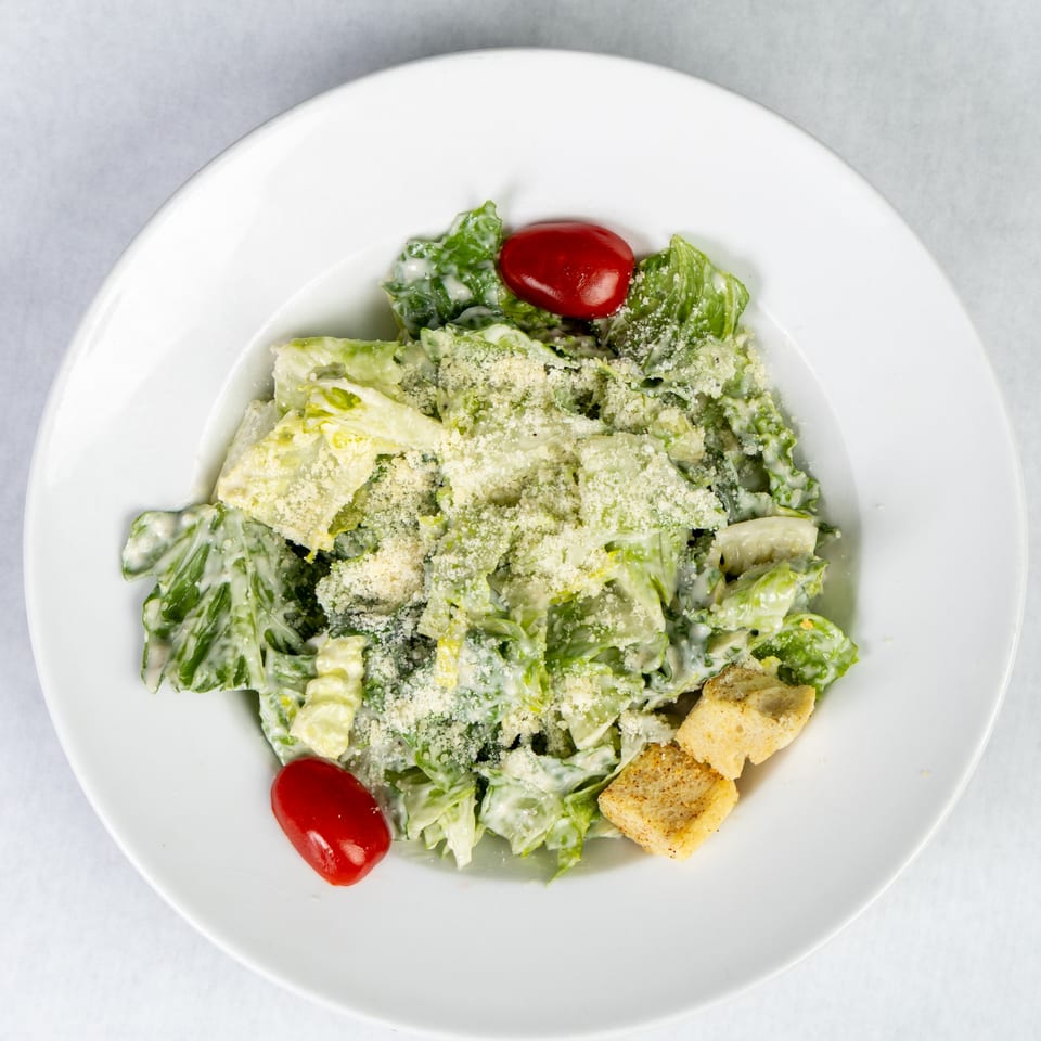 Caesar salad with romaine lettuce, creamy dressing, grated cheese, croutons, and cherry tomatoes.