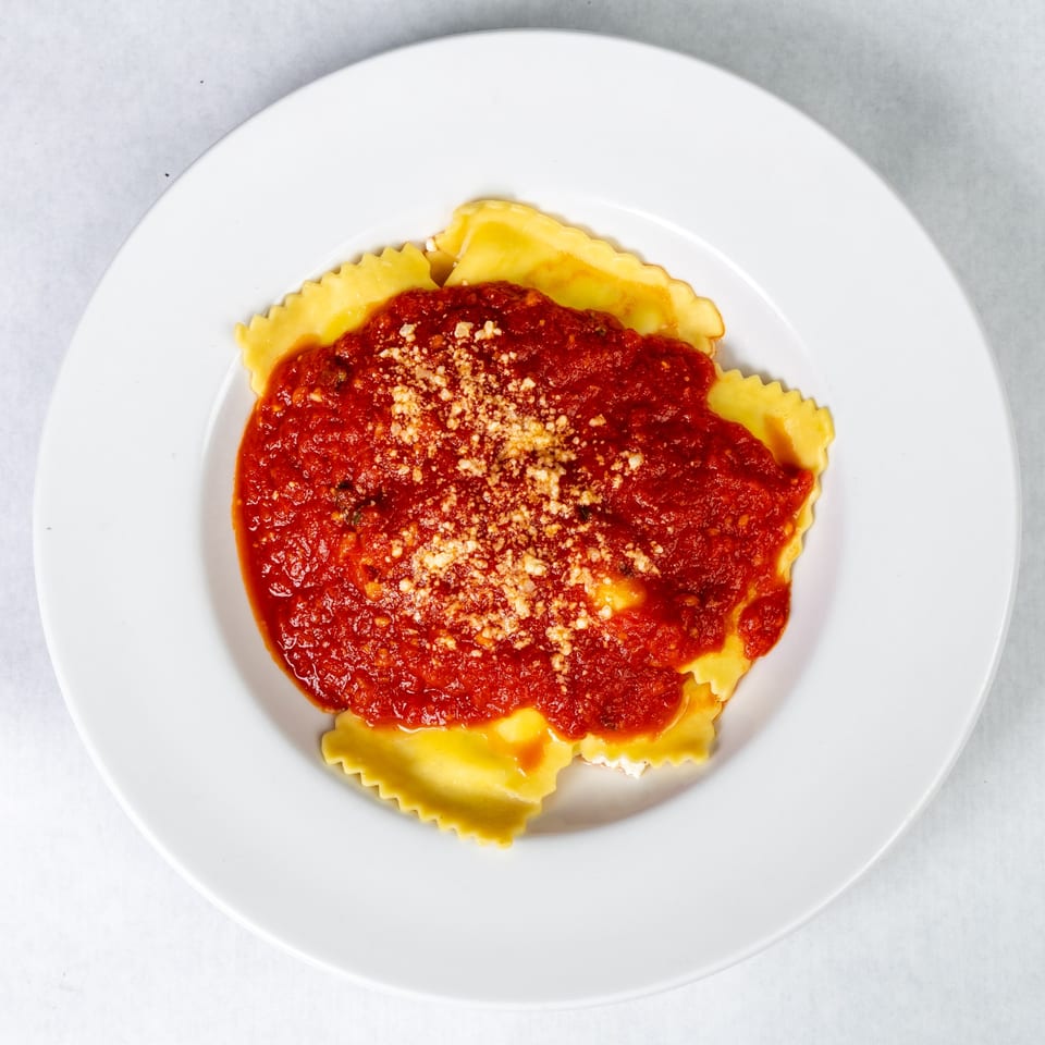 Abbondanza Cucina's ravioli dish, topped with rich red sauce and grated Parmesan cheese.